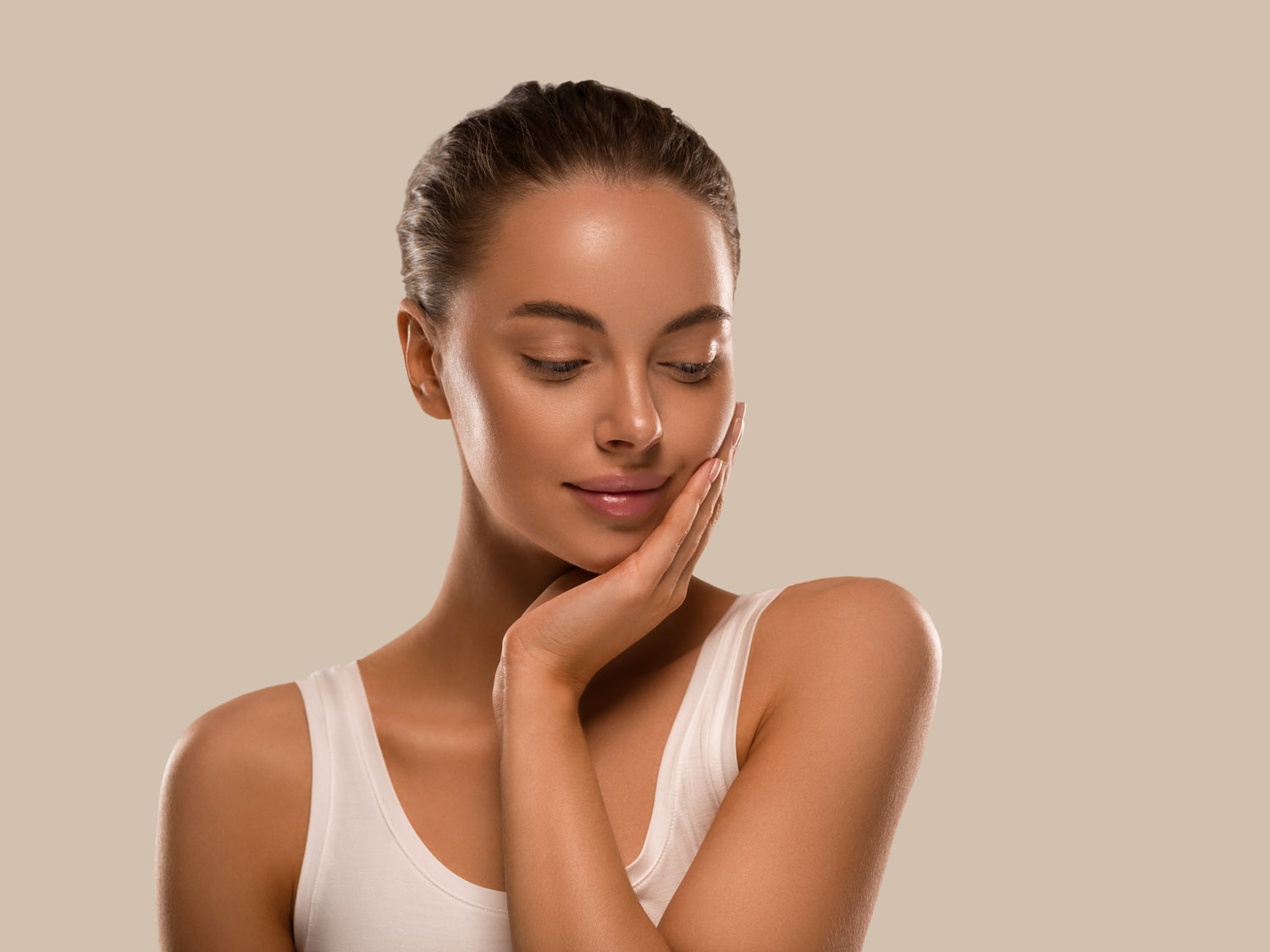 Beautiful woman with healthy fresh skin and natural makeup, gently touching her face with her hands, showcasing clean beauty and skincare.